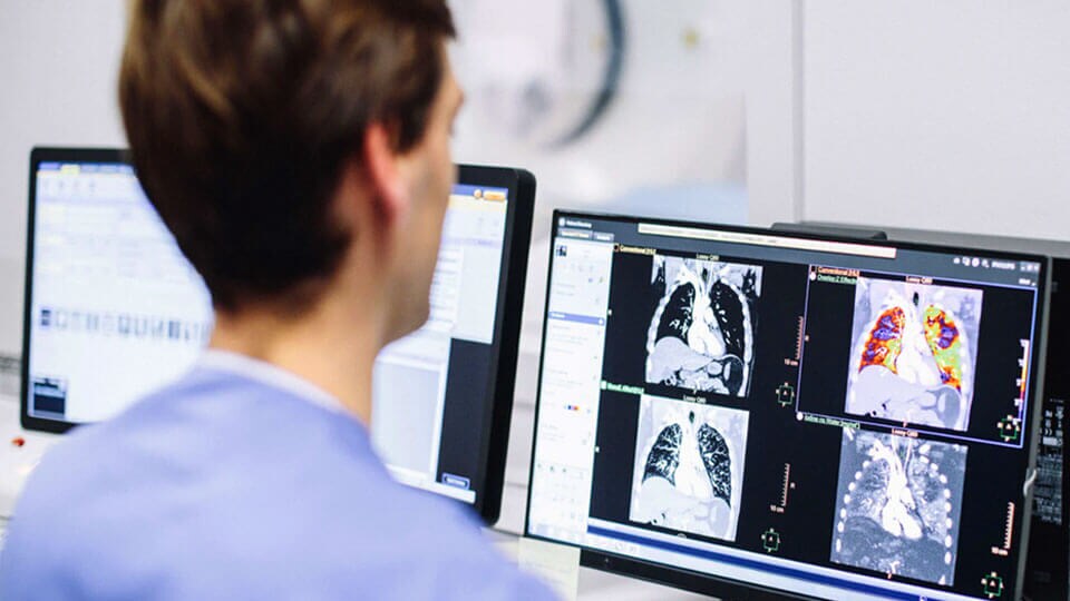 Photo of technologist reviewing CT clinical images on a monitor